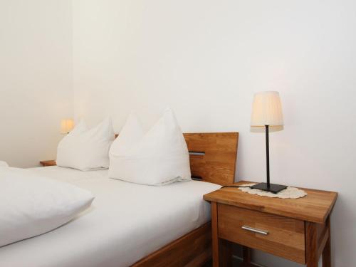 a bed with white sheets and a lamp on a night stand at Apartment Liebl-4 by Interhome in Seefeld in Tirol