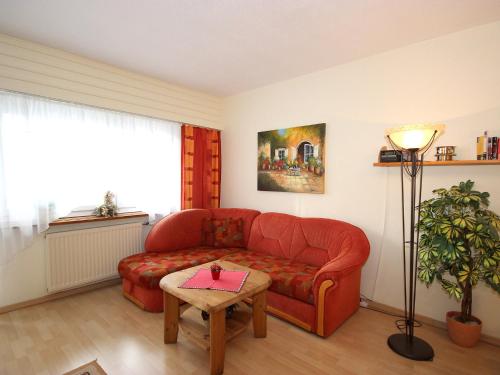 ein Wohnzimmer mit einem roten Sofa und einem Tisch in der Unterkunft Apartment Am Birkenhain-28 by Interhome in Seefeld in Tirol