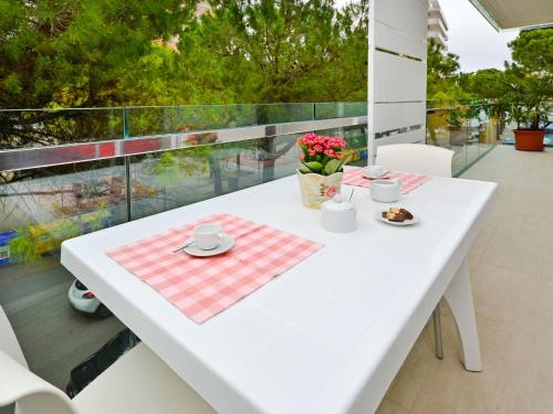 uma mesa branca com um prato de comida numa varanda em Apartment Fiore-2 by Interhome em Lignano Sabbiadoro