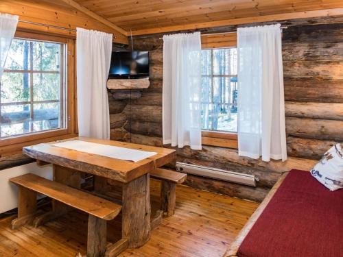 a wooden room with a wooden table and windows at Holiday Home Retkietappi honkapirtti by Interhome in Juuma