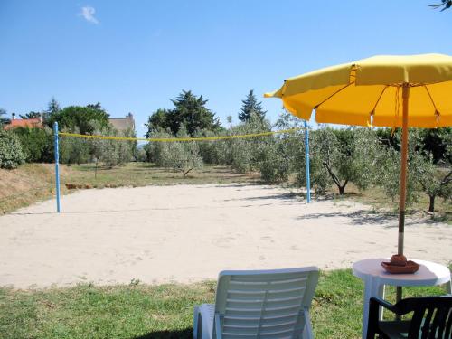 a table with a yellow umbrella and chairs in front of a beach at Apartment Le Macine-4 by Interhome in Cecina