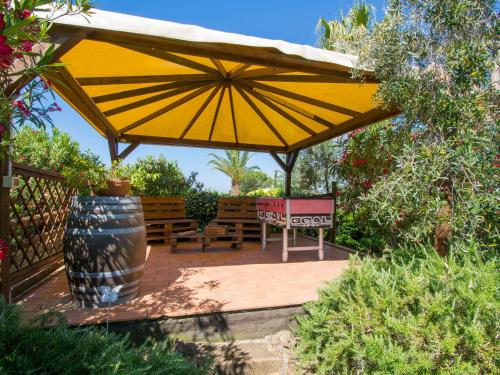 a patio with a yellow umbrella and benches at Apartment Le Macine-4 by Interhome in Cecina