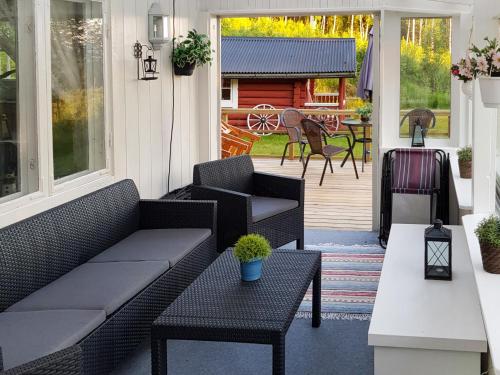 un porche cubierto con sofá y mesas en Chalet Höje - VMD220 by Interhome en Hagfors