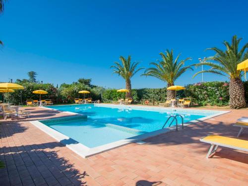 a large swimming pool with umbrellas and palm trees at Apartment Le Macine-2 by Interhome in Cecina