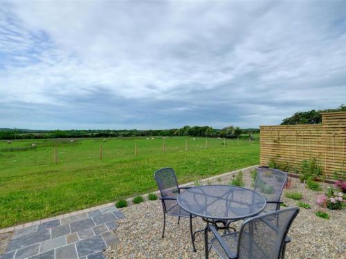 a table and chairs on a patio with a field at Holiday Home Palmerston Primrose by Interhome in Haverfordwest