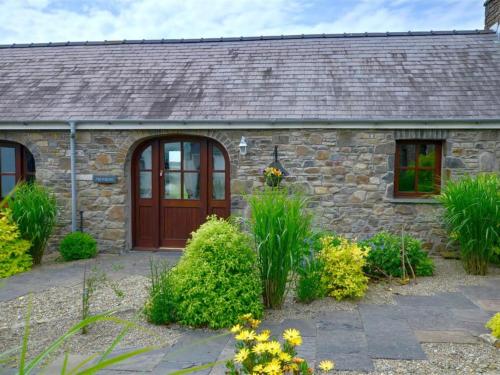 a stone house with a wooden door and some plants at Holiday Home Palmerston Primrose by Interhome in Haverfordwest