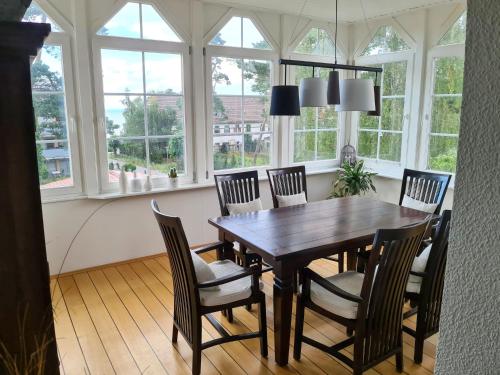 comedor con mesa, sillas y ventanas en Apartment Villa am Meer by Interhome en Lubmin