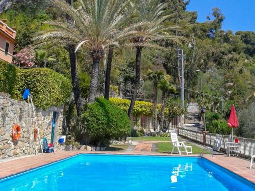 einen blauen Pool mit Palmen und einem Stuhl in der Unterkunft Apartment Belvedere by Interhome in Mortola Inferiore