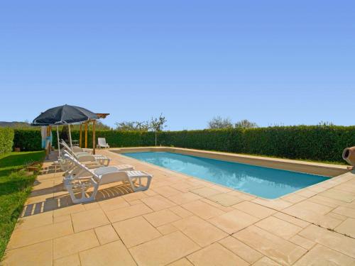 a swimming pool with two chairs and an umbrella at Holiday Home Lucia by Interhome in Cortona