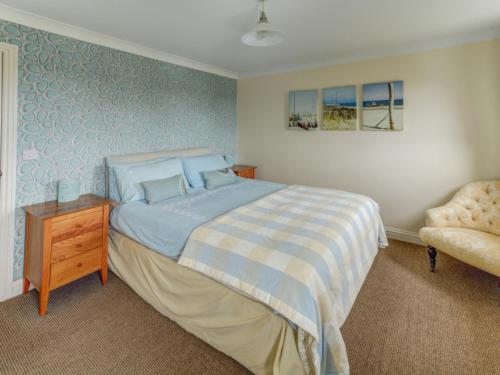 a bedroom with a bed and a chair at Holiday Home Valentines Cottage by Interhome in Braunton