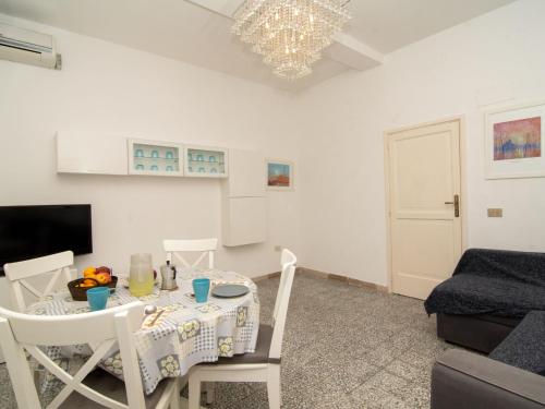 un soggiorno con tavolo, sedie e lampadario pendente di Apartment Carlino by Interhome a Nerano
