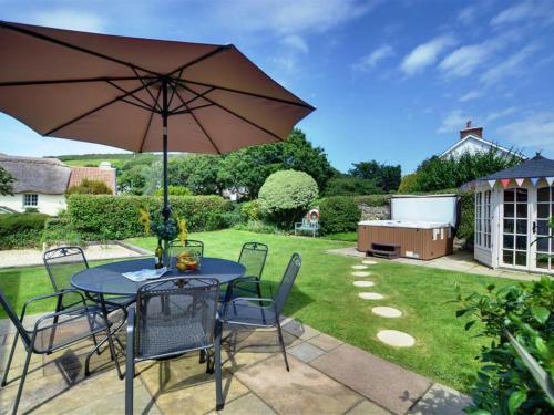 a table and chairs with an umbrella in a yard at Holiday Home Watery Lane by Interhome in Croyde