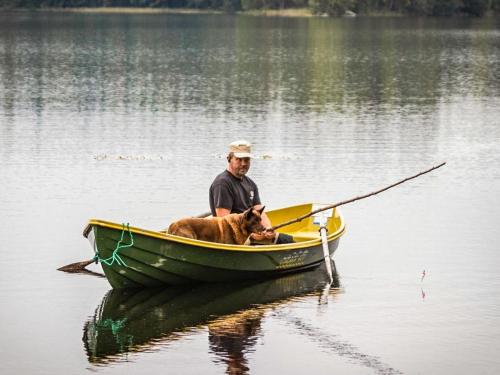 a man and a dog in a boat in the water at Holiday Home Kuikanranta by Interhome in Hara