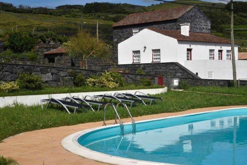 a swimming pool with chairs in front of a house at Quinta das figueiras in Velas