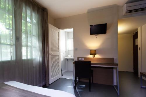 a room with a desk and a television on the wall at Hotel Restaurant du Centre et du Lauragais in Castelnaudary