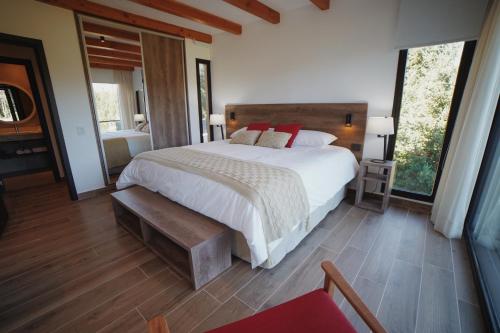 a bedroom with a large white bed with red pillows at AWKA Apart Hotel in Villa La Angostura