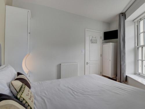 a white bedroom with a large bed and a window at Apartment Belle View by Interhome in Ilfracombe