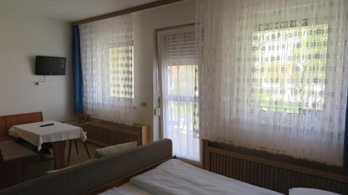 a bedroom with a bed and a table and windows at Gästehaus Andreas Kroiss in Illmitz