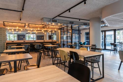 a restaurant with wooden tables and chairs and windows at Tulip Residences Joinville-Le-Pont in Joinville-le-Pont
