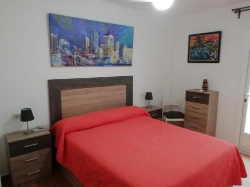 Un dormitorio con una cama roja y una pintura en la pared en Apartamento naturista Vera Playa, en Vera