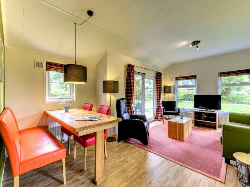 ein Wohnzimmer mit einem Tisch, Stühlen und einem TV in der Unterkunft Holiday Home Buitenplaats Gerner-3 by Interhome in Dalfsen