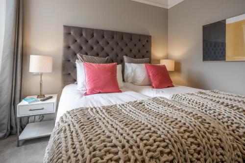 a bedroom with a large bed with two red pillows at No1 Apartments & Bedrooms St Andrews - St Mary's in St. Andrews