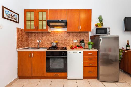 a kitchen with wooden cabinets and a stainless steel refrigerator at Apartment & Rooms Graciela in Rovinj
