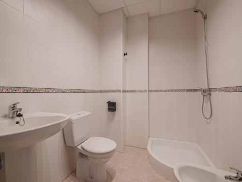 a white bathroom with a toilet and a shower at Apartamentos Santiago in Écija