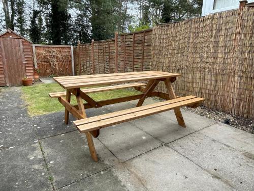 a wooden picnic table in front of a fence at Walsingham House - Modern 2 Bed - Driveway Parking - Marvello Properties in Norwich