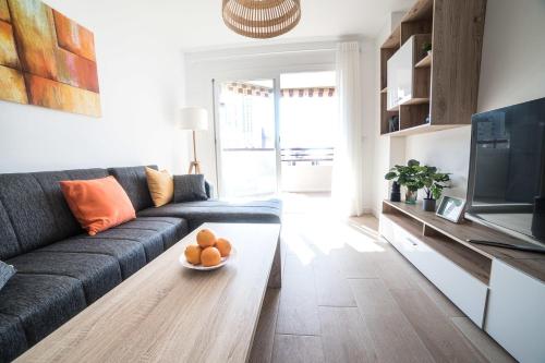 una sala de estar con sofá y un cuenco de naranjas sobre una mesa en Moonkey - Apartamento Las Naranjas, en Benidorm