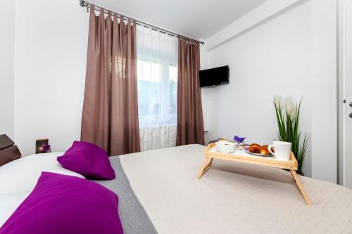 a bedroom with a bed with purple pillows and a tray of food at Apartment & Rooms Graciela in Rovinj