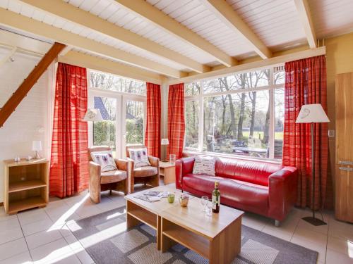 uma sala de estar com um sofá vermelho e uma mesa em Holiday Home Buitenplaats Gerner-7 by Interhome em Dalfsen