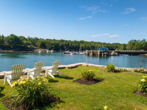 two white chairs sitting on the grass by the water at Inn at Diamond Cove in Portland