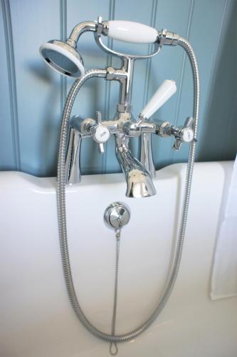 a shower in a bath tub with a shower head at 136 West Princes Street in Helensburgh