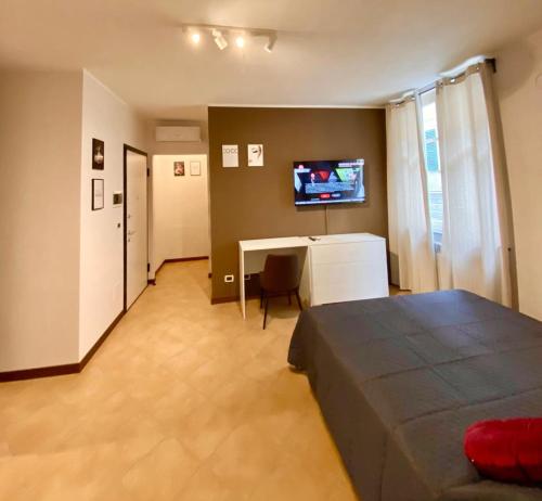 um quarto com uma cama, uma mesa e uma televisão em HH Hermoso Housing SERRAVALLE em Serravalle Scrivia