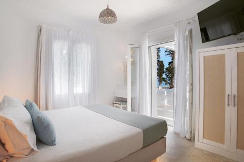 a white bedroom with a bed and a sliding glass door at Votsalo Seaside in Steniaí
