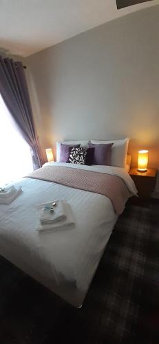 a bedroom with a large white bed with two lamps at Beach Cove in Llandudno