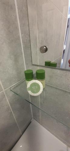 three green cups sitting on a glass shelf in a bathroom at Beach Cove in Llandudno