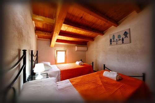 two beds in a room with wooden ceilings at Villa Maddy in Avola