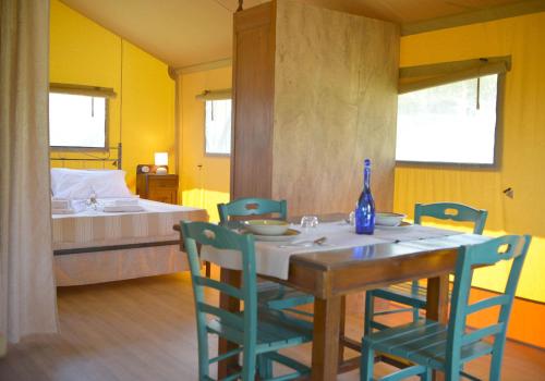 a dining room with a table and chairs and a bed at Glamping Tenuta San Pierino Agriturismo in Rosignano Marittimo