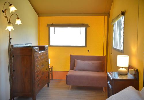a bedroom with a couch and a dresser and a window at Glamping Tenuta San Pierino Agriturismo in Rosignano Marittimo