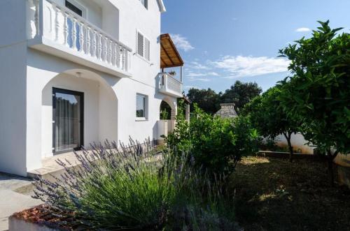 a white building with a balcony and a yard at Apartments Lemeš in Drače