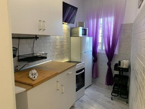 eine Küche mit einem weißen Kühlschrank und lila Vorhängen in der Unterkunft DREAM SMILE in Santa Cruz de Tenerife