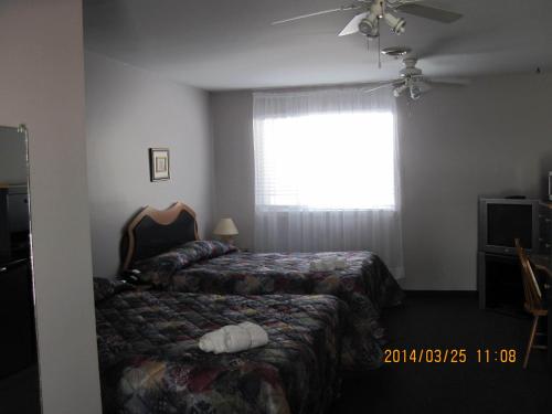 A bed or beds in a room at Motel Parc Beaumont Inc.