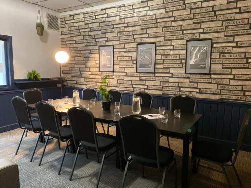 a dining room with tables and chairs and a brick wall at The Embassy Hotel in Hull