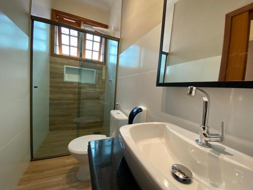 a bathroom with a sink and a toilet and a mirror at Pousada Maria Monteiro Tiradentes in Tiradentes