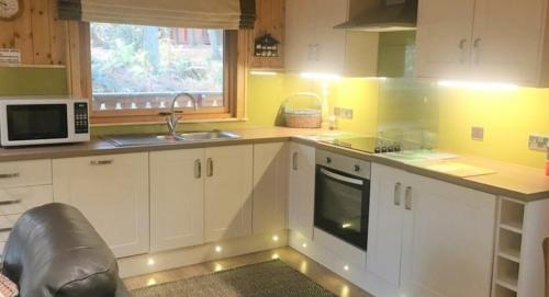 a kitchen with white cabinets and a sink and a microwave at Fern Lodge in Louth