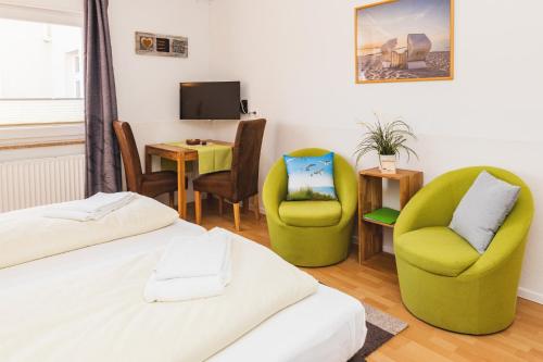 a room with two beds and chairs and a television at Skerra Apartments "am Fitness-Studio" in Fehmarn