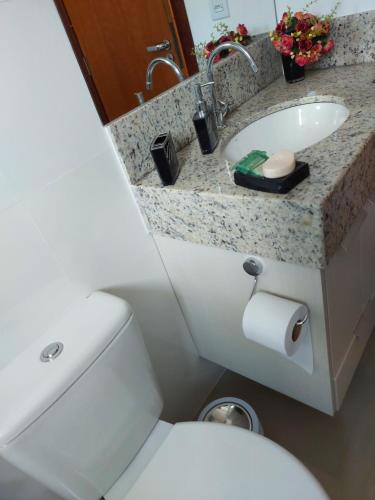 uma casa de banho com um WC branco e um lavatório. em Quarto da GABI em Capitólio