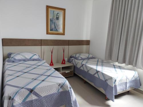a bedroom with two beds and a picture on the wall at Quarto da GABI in Capitólio